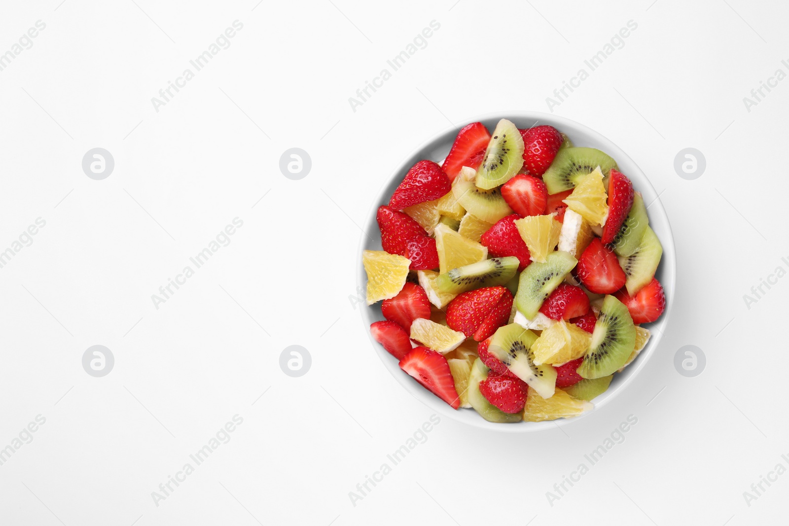 Photo of Yummy fruit salad in bowl on white background, top view. Space for text