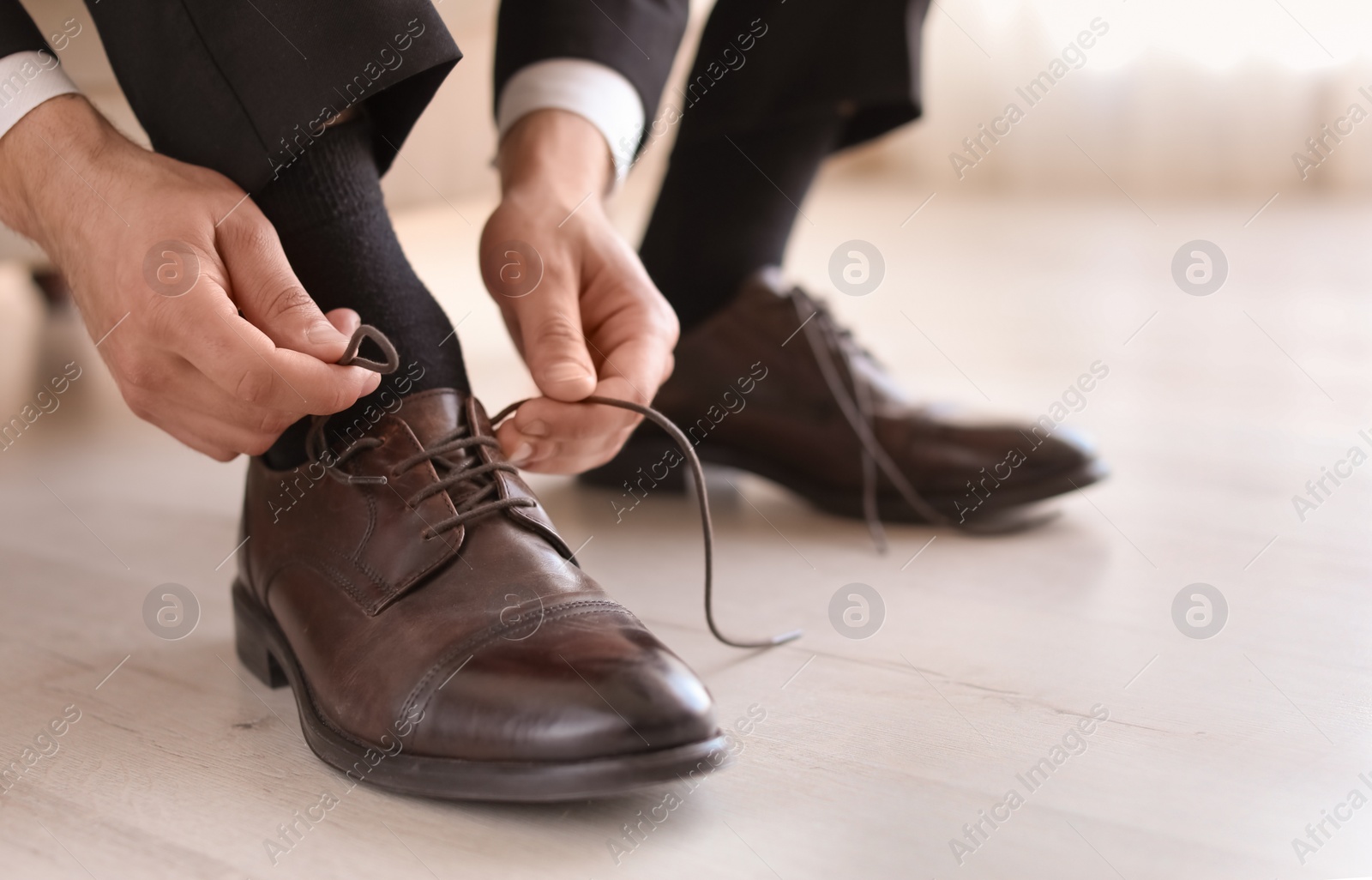 Photo of Man putting on elegant leather shoes indoors, closeup