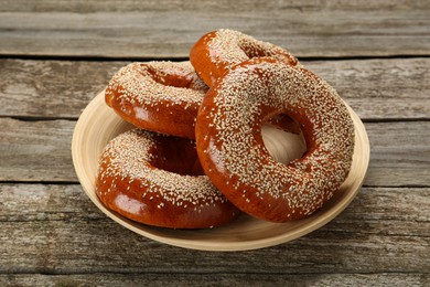 Photo of Delicious fresh bagels with sesame seeds on wooden table