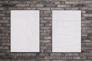 Image of Blank creased posters on grey brick wall. Mockup for design 