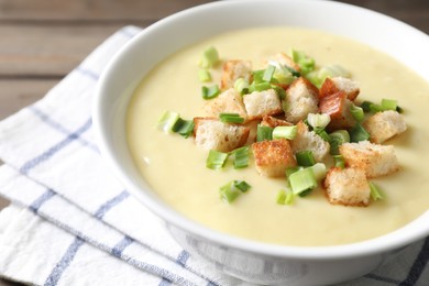 Photo of Tasty potato soup with croutons and green onion in bowl on table, closeup