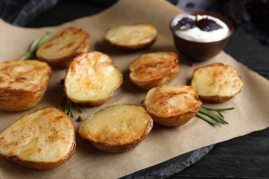 Photo of Delicious potato wedges with sour cream on black wooden table, closeup