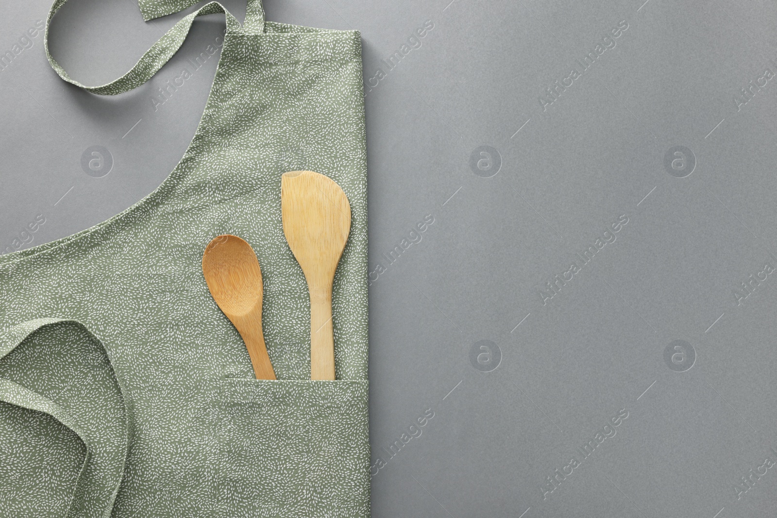 Photo of Clean apron with wooden kitchen tools on light grey background, top view. Space for text