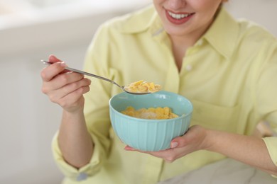 Photo of Smiling woman eating tasty cornflakes at breakfast on blurred background, closeup