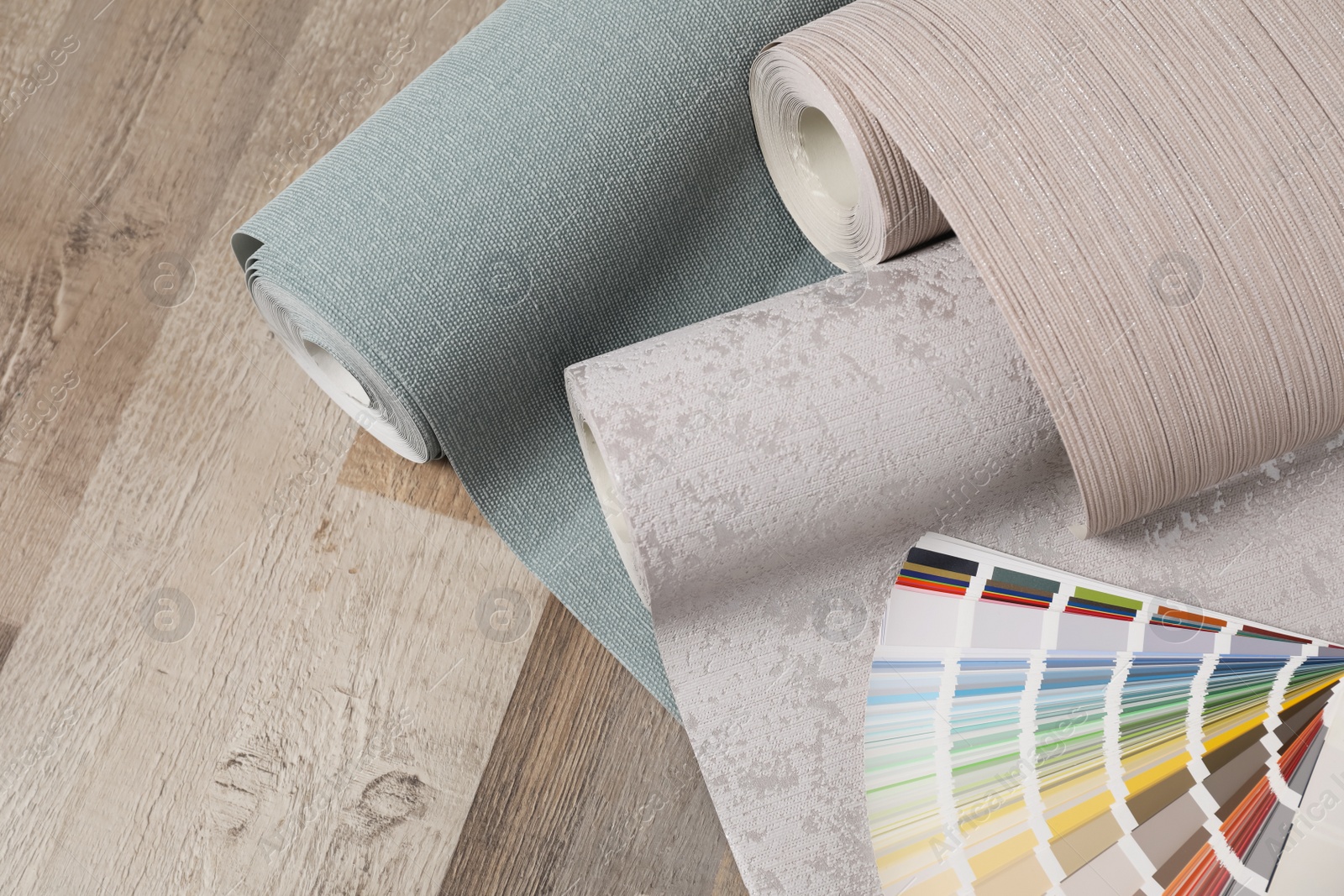 Photo of Wall paper rolls and color palette on wooden floor