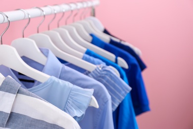 Rack with bright clothes on color background