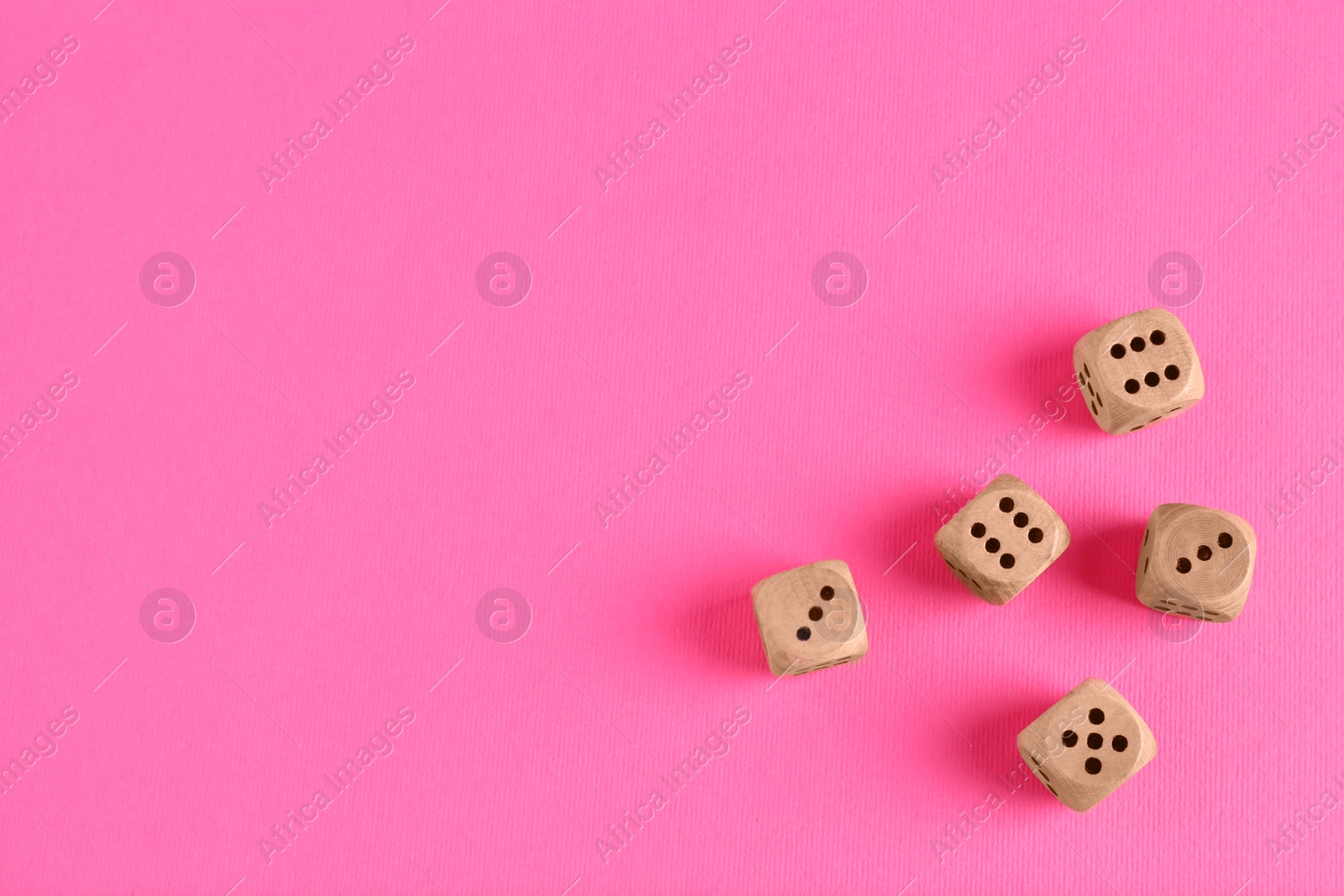 Photo of Many wooden game dices on pink background, flat lay. Space for text