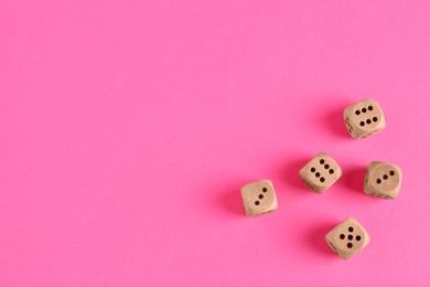 Photo of Many wooden game dices on pink background, flat lay. Space for text