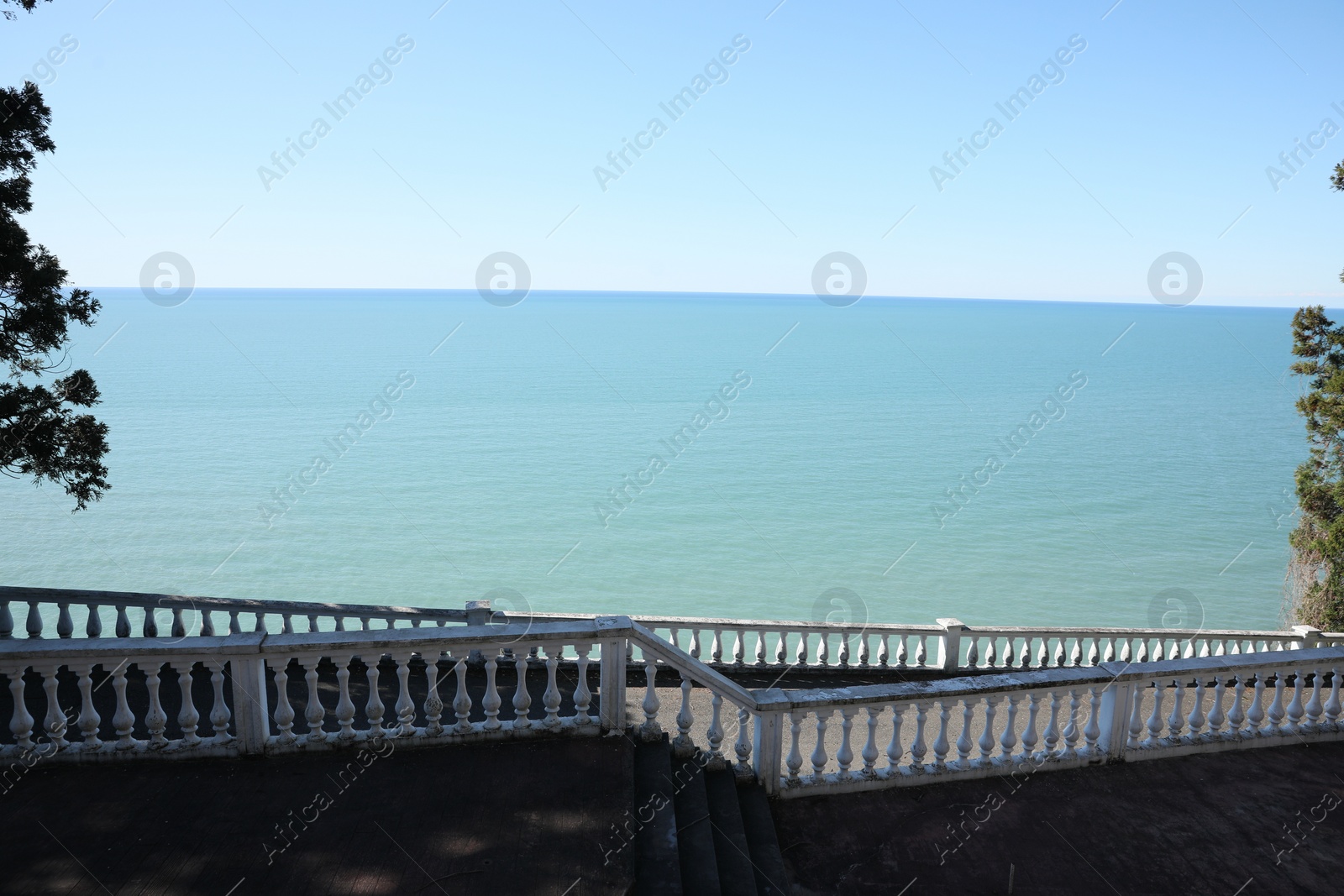 Photo of White railings and stairs near calm sea on sunny day