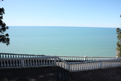 Photo of White railings and stairs near calm sea on sunny day