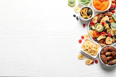 Photo of Bowls of different dried fruits on wooden background, top view with space for text. Healthy lifestyle