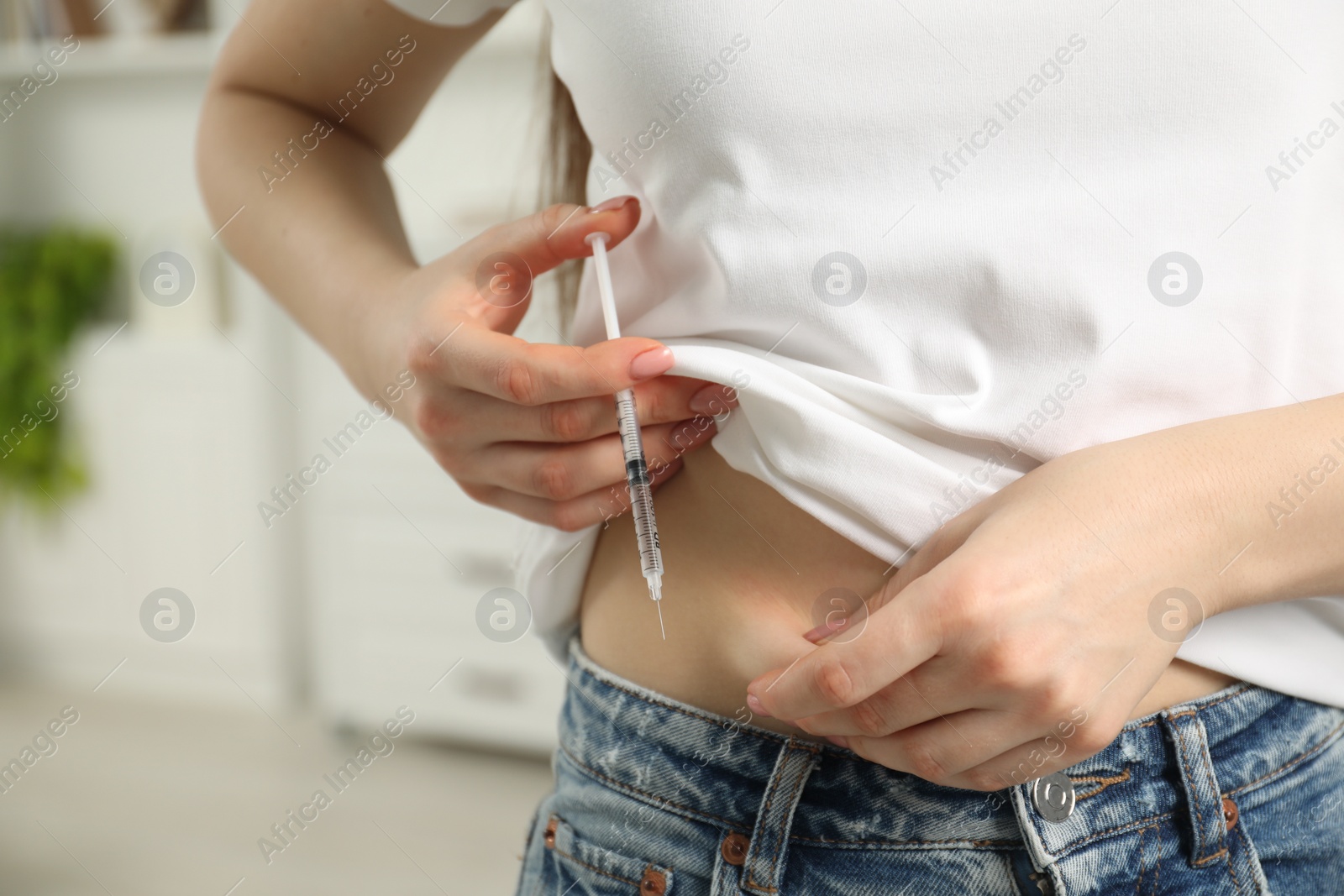 Photo of Diabetes. Woman making insulin injection into her belly indoors, closeup