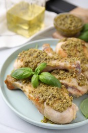 Photo of Delicious fried chicken drumsticks with pesto sauce and basil on table