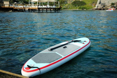 Photo of One SUP board with paddle near sea shore