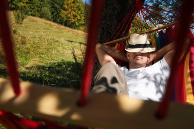 Photo of Man resting in hammock outdoors on sunny day