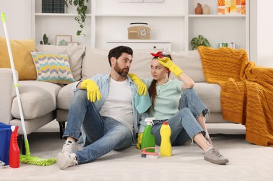 Photo of Spring cleaning. Tired couple with detergents and mop in living room