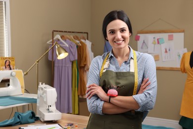 Photo of Professional dressmaker with measuring tape and pin cushion in workshop