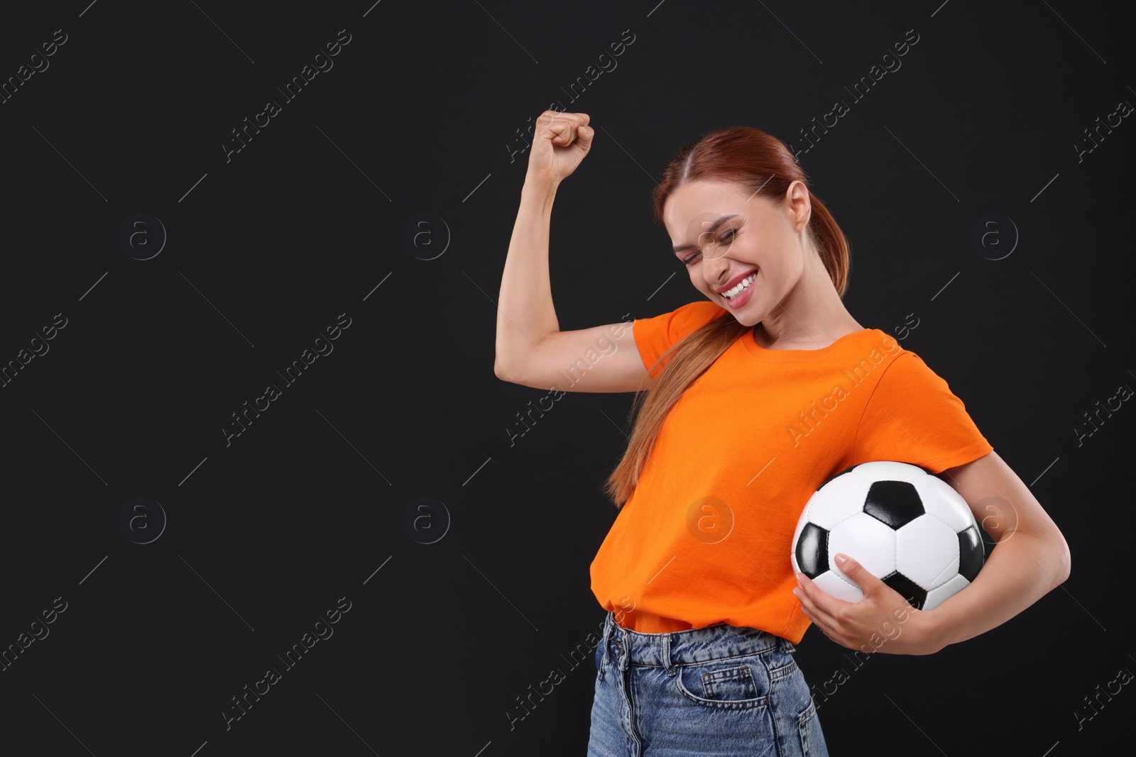 Photo of Happy fan with football ball on black background, space for text