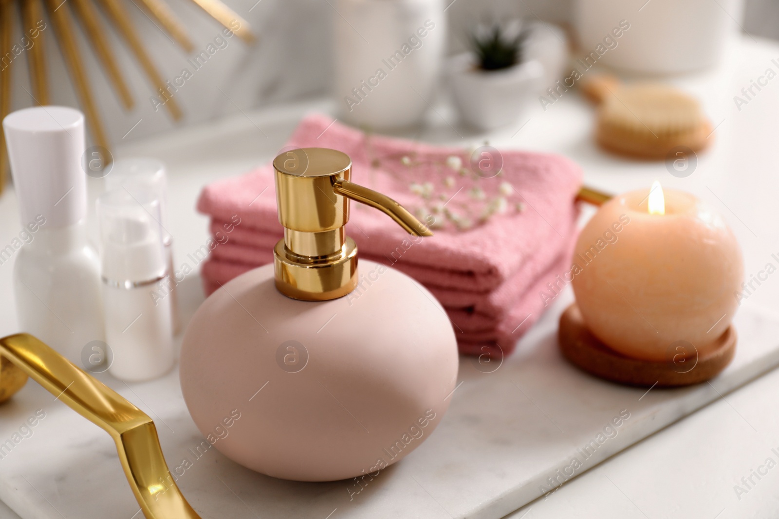 Photo of Tray with soap dispenser, burning candle and towels on countertop in bathroom, closeup