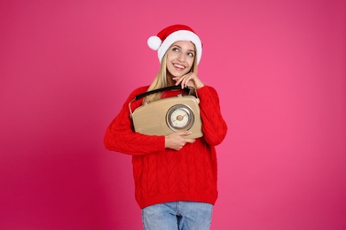 Happy woman with vintage radio on pink background. Christmas music