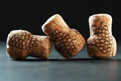 Photo of Corks of wine bottles with grape images on black table, closeup