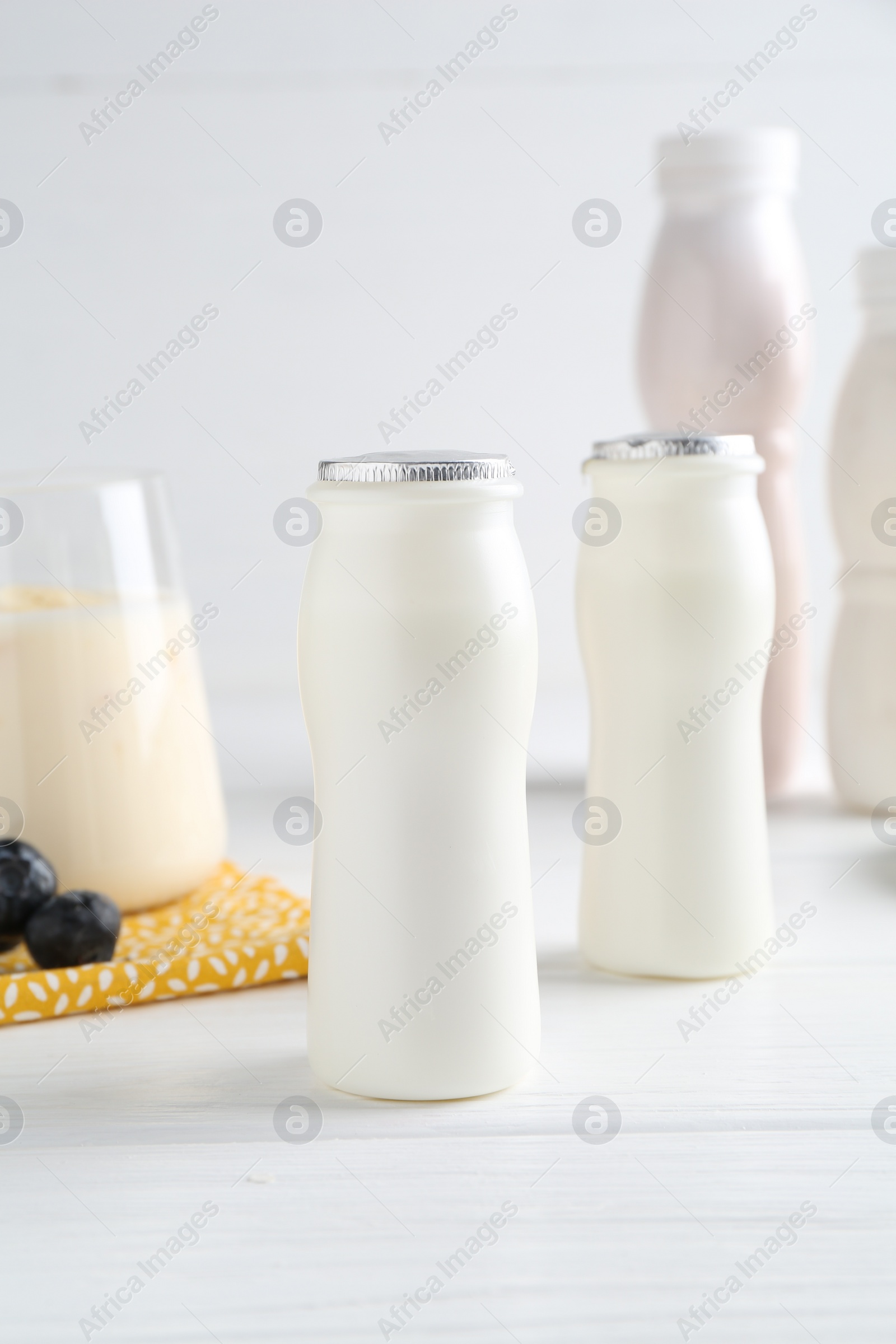 Photo of Tasty yogurt in bottles and blueberries on white wooden table