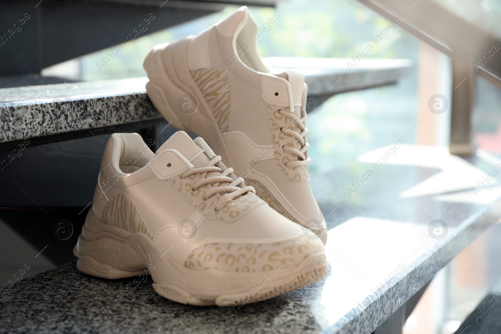 Photo of Pair of stylish women's sneakers on grey marble stairs indoors