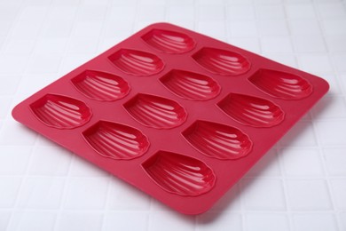 Photo of Red baking mold for madeleine cookies on white tiled table, closeup