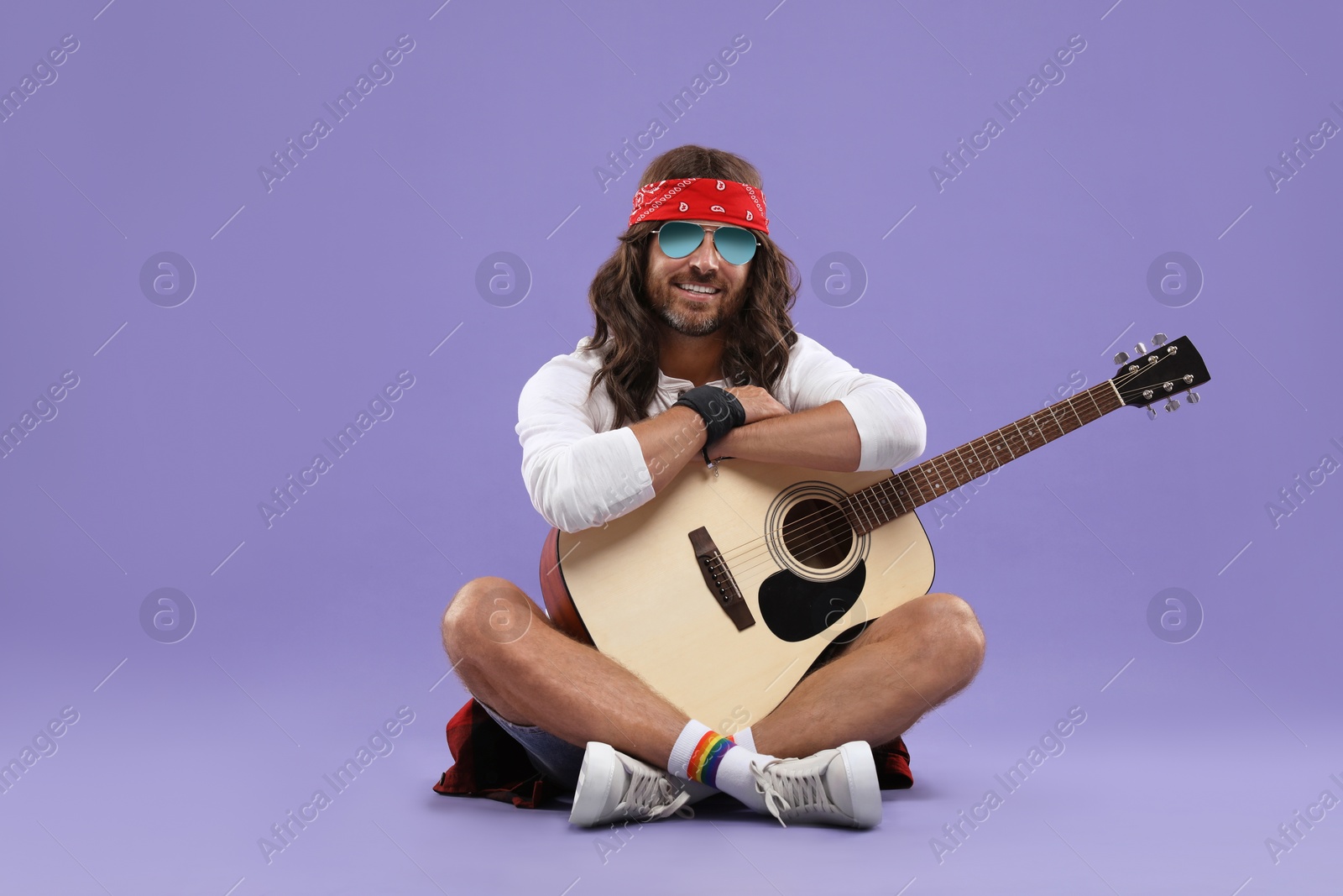 Photo of Stylish hippie man with guitar on violet background