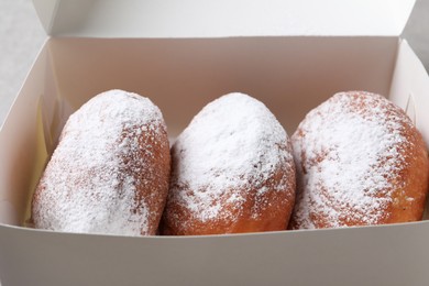 Photo of Delicious sweet buns with powdered sugar in box, closeup