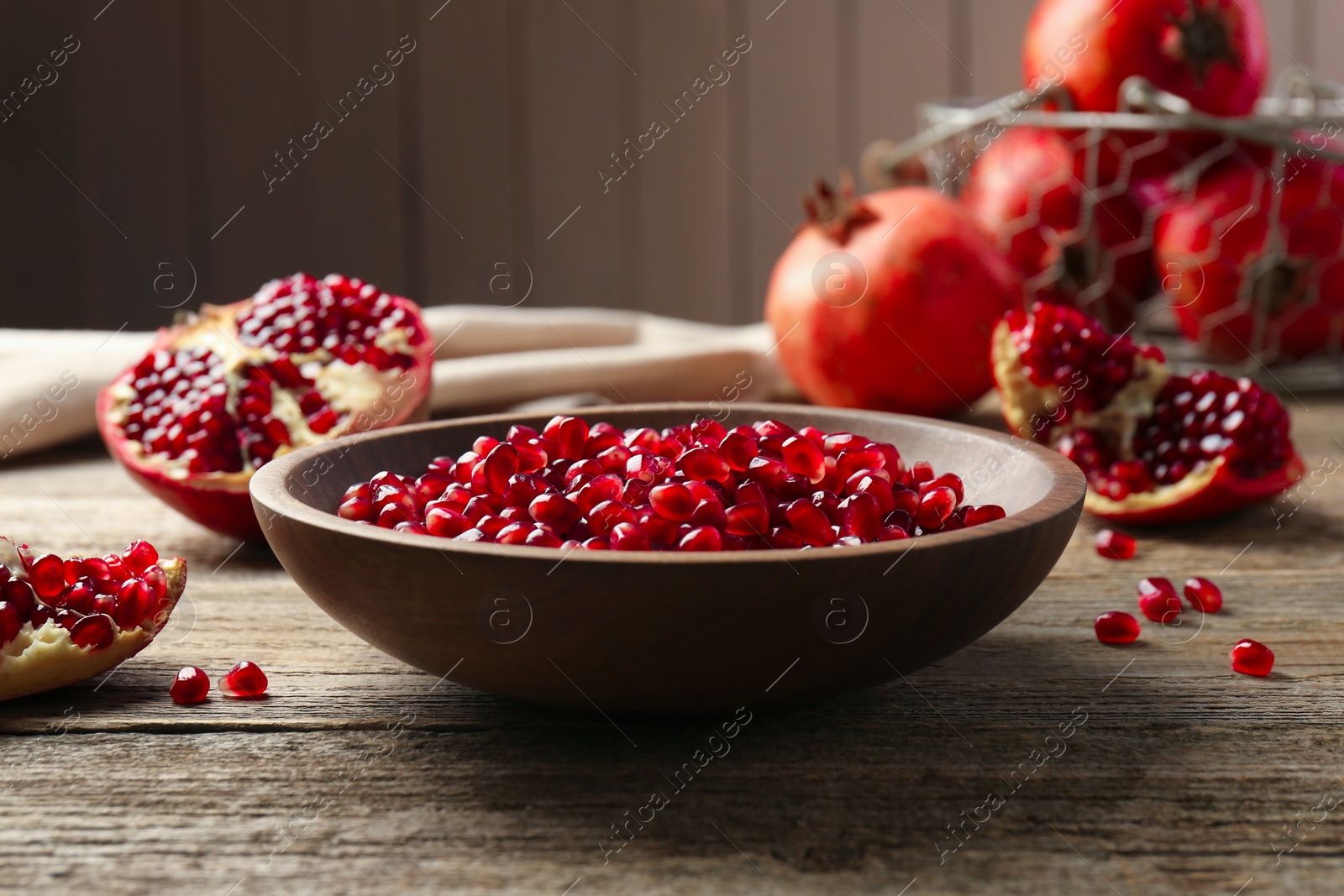 Photo of Ripe juicy pomegranate grains in bowl on wooden table