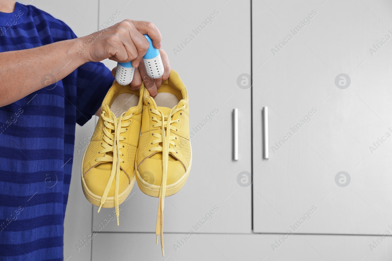 Photo of Woman putting capsule shoe freshener in footwear indoors, closeup