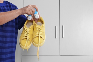 Photo of Woman putting capsule shoe freshener in footwear indoors, closeup