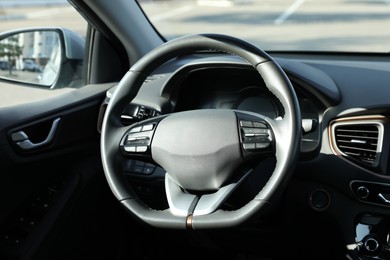 Photo of Black steering wheel and dashboard in modern car