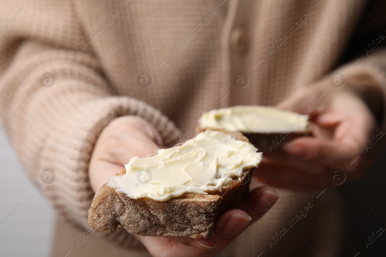 Photo of Woman holding slices of bread with butter, closeup