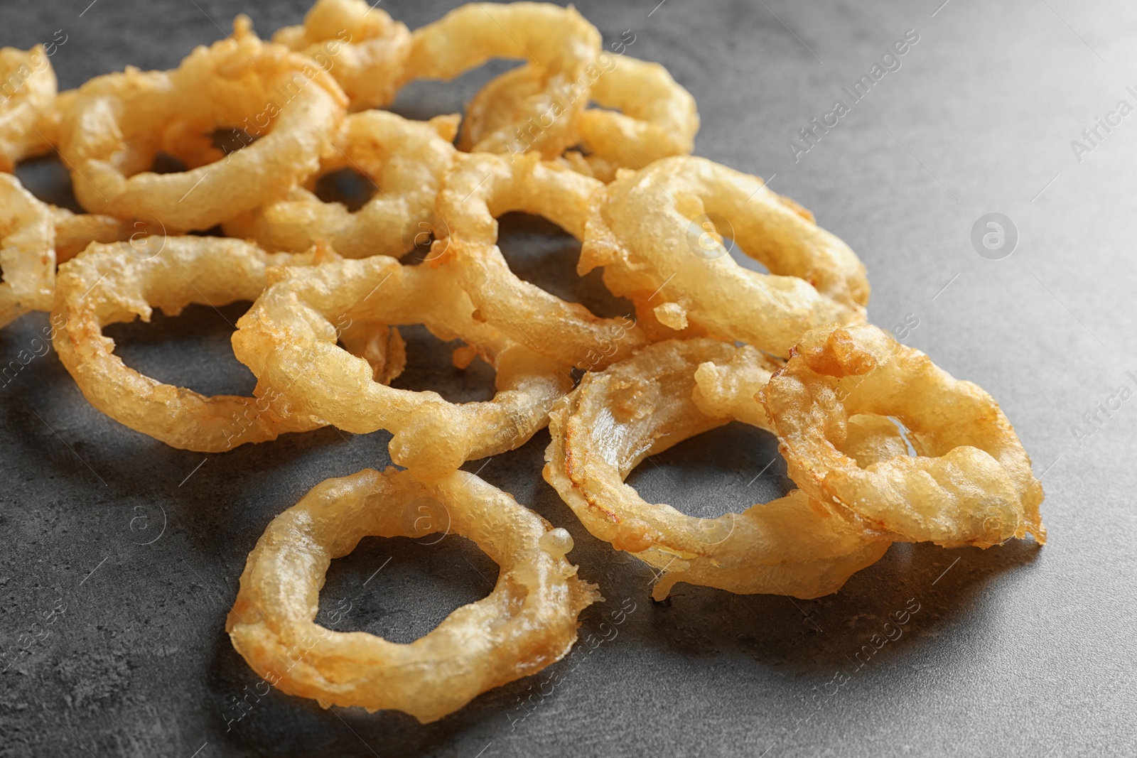 Photo of Delicious golden breaded and deep fried crispy onion rings on gray background, closeup