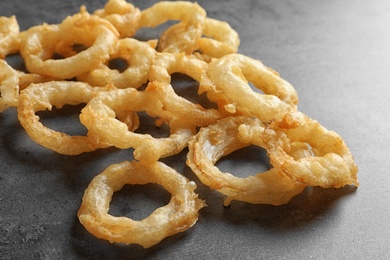 Delicious golden breaded and deep fried crispy onion rings on gray background, closeup