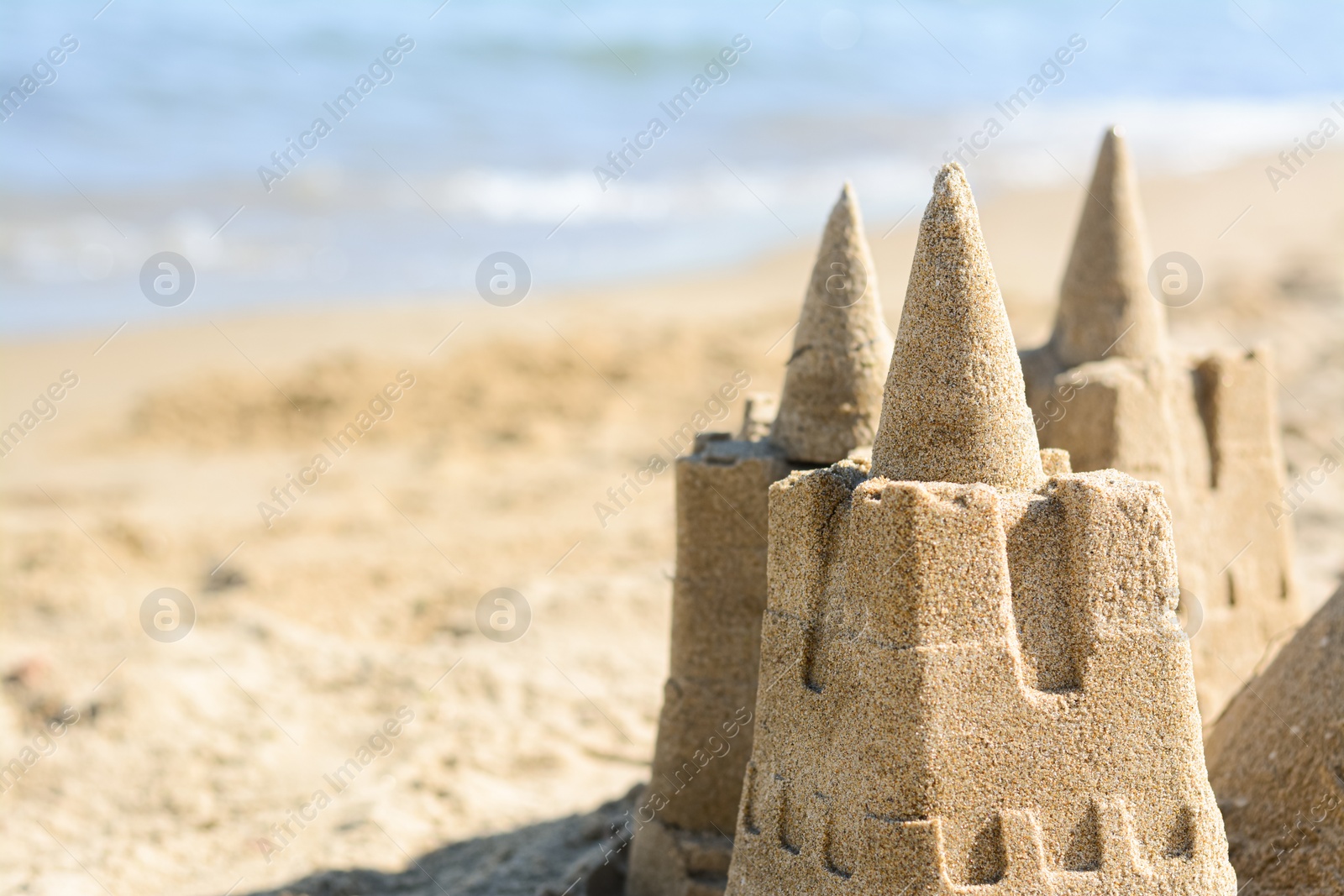 Photo of Beach with sand castle near sea on sunny day, closeup. Space for text