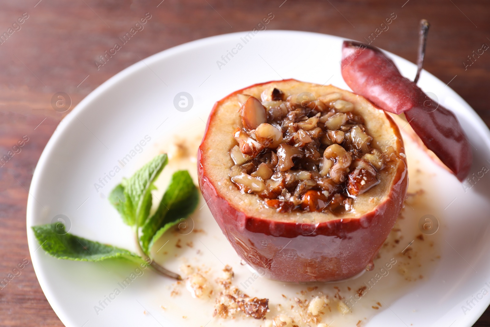 Photo of Tasty baked apple with nuts, honey and mint on table, closeup