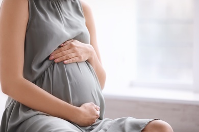 Photo of Young pregnant woman at home, closeup