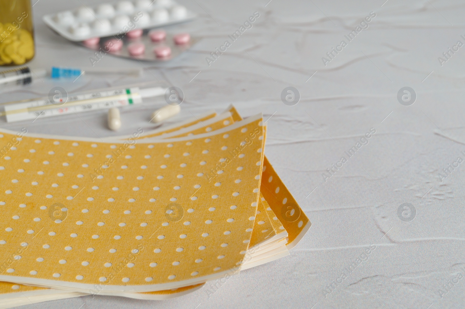 Photo of Yellow mustard plaster on light gray table, closeup. Space for text