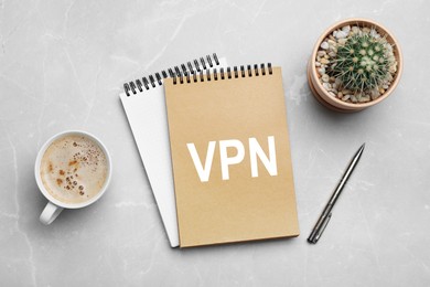 Notebook with acronym VPN on light grey marble table, flat lay. Secure network connection