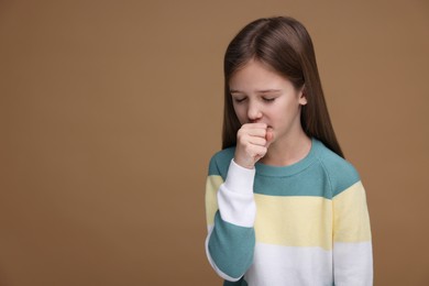 Photo of Sick girl coughing on brown background, space for text