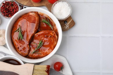 Photo of Flat lay composition with raw marinated meat in bowl, spices and basting brush on white tiled table. Space for text