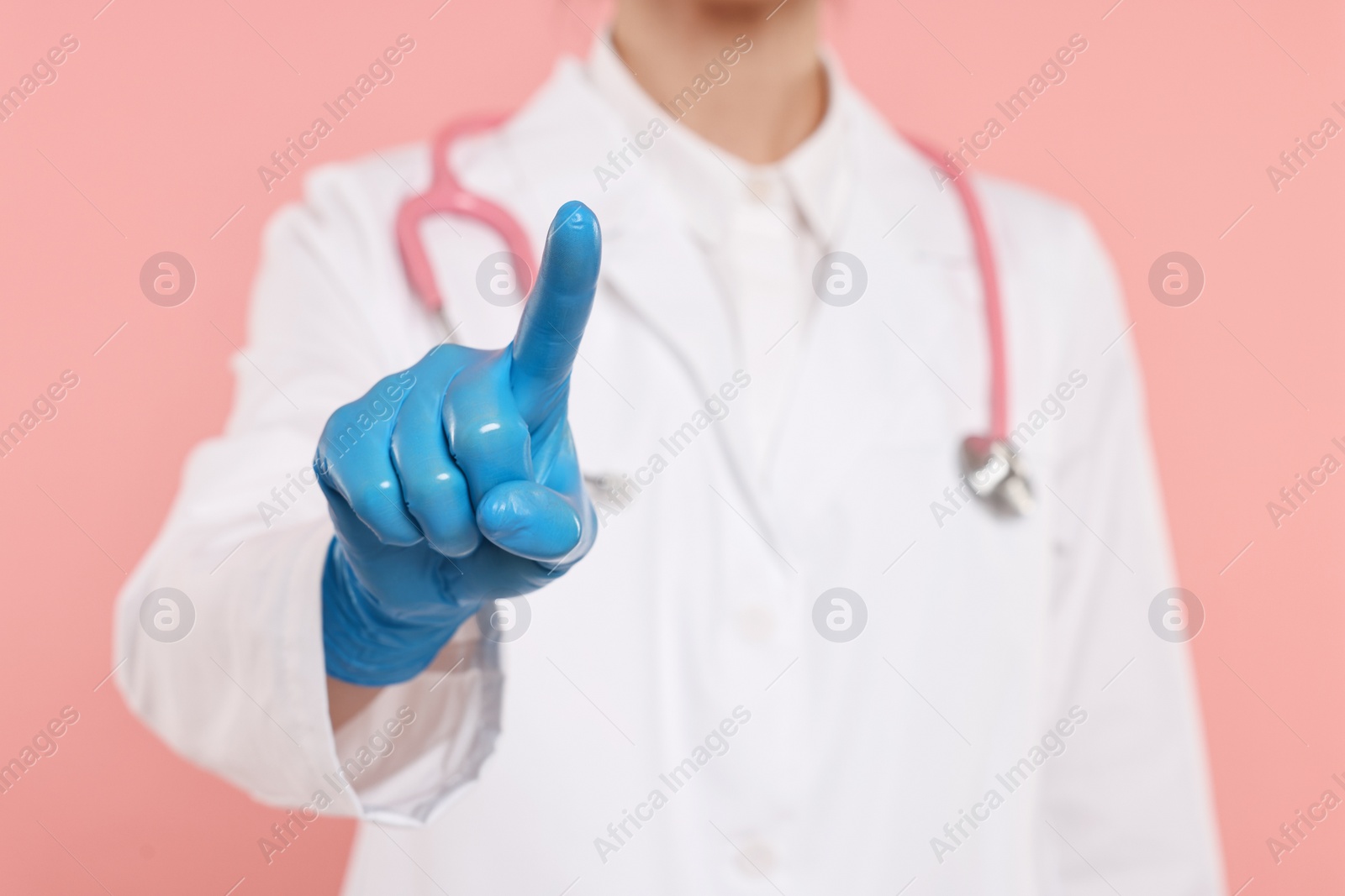 Photo of Doctor with stethoscope pointing on pink background, closeup