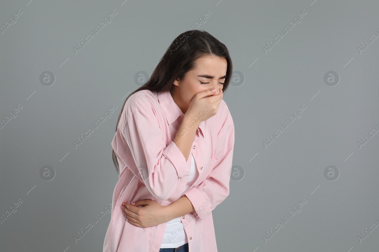 Photo of Young woman suffering from stomach ache and nausea on grey background. Food poisoning