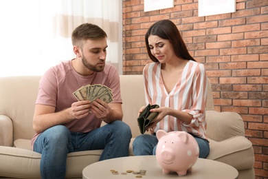 Photo of Unhappy young couple with money at home. Financial problems