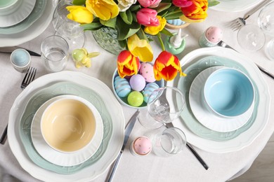 Festive Easter table setting with beautiful flowers and painted eggs, top view