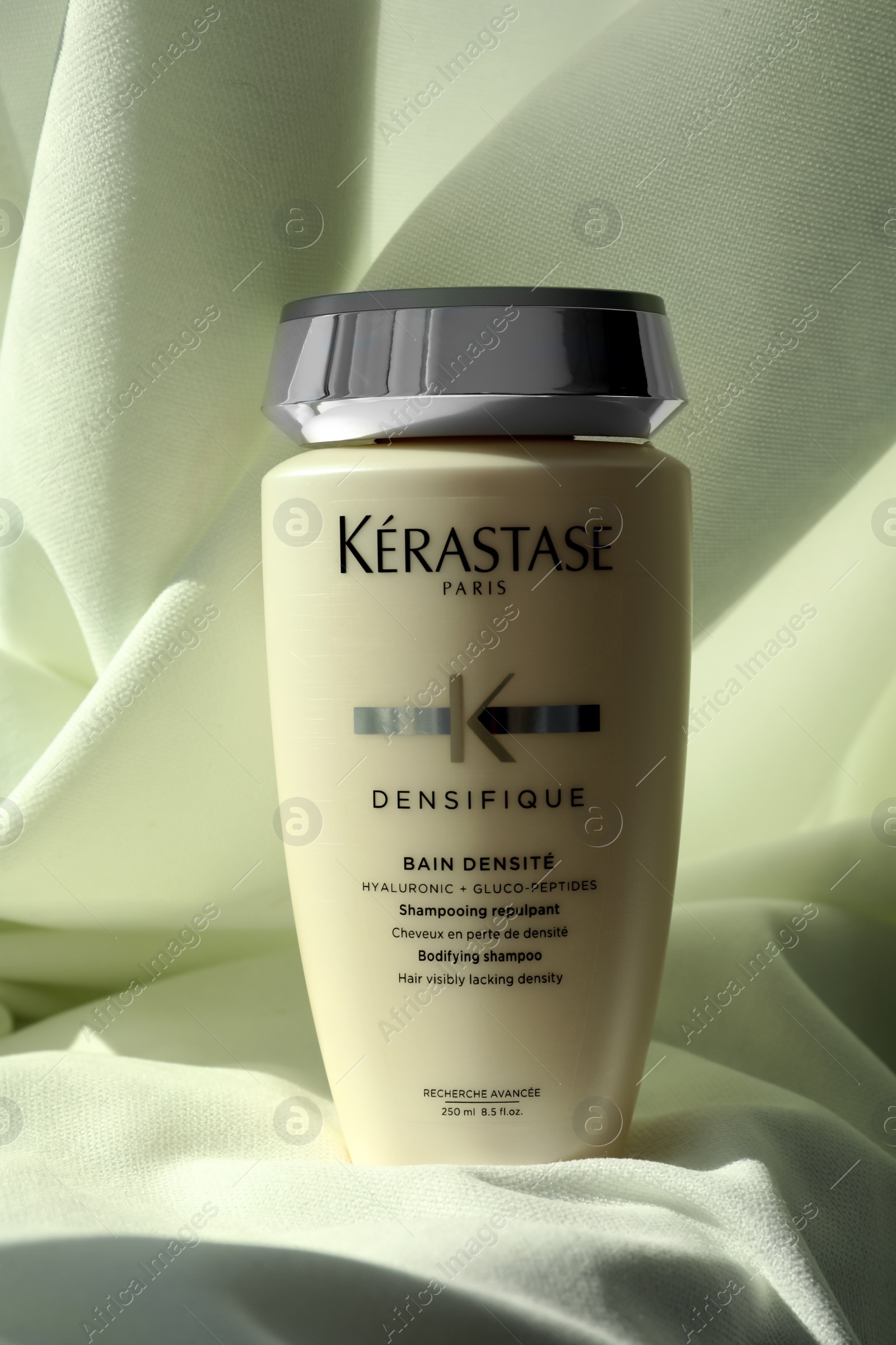 Photo of MYKOLAIV, UKRAINE - SEPTEMBER 07, 2021: Kerastase shampoo on white fabric. Hair care cosmetic product