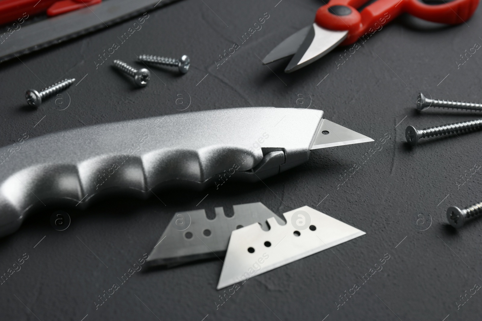 Photo of Utility knife with blades among other tools on grey background